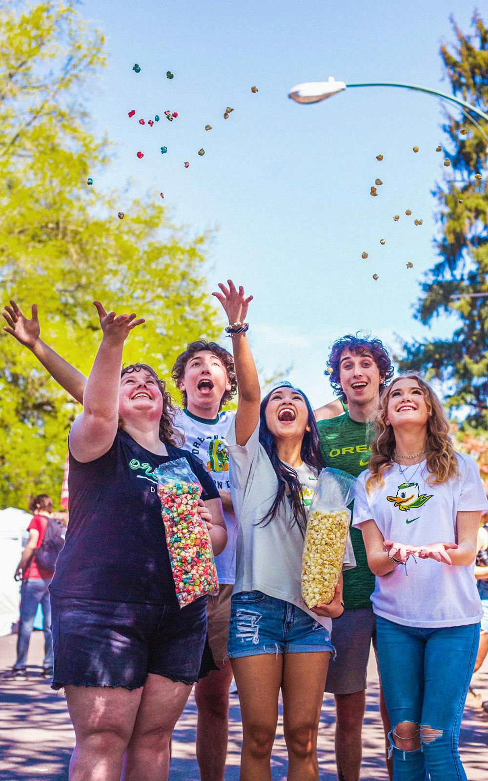 A group of students throwing popcorn in the air at the University of Oregon Street Faire