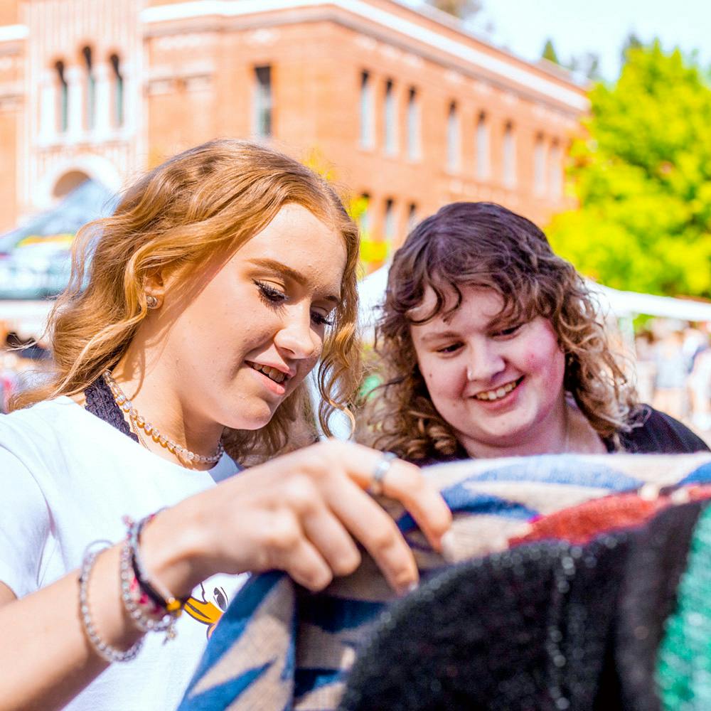 Two University of Oregon students looking at products at the street fair